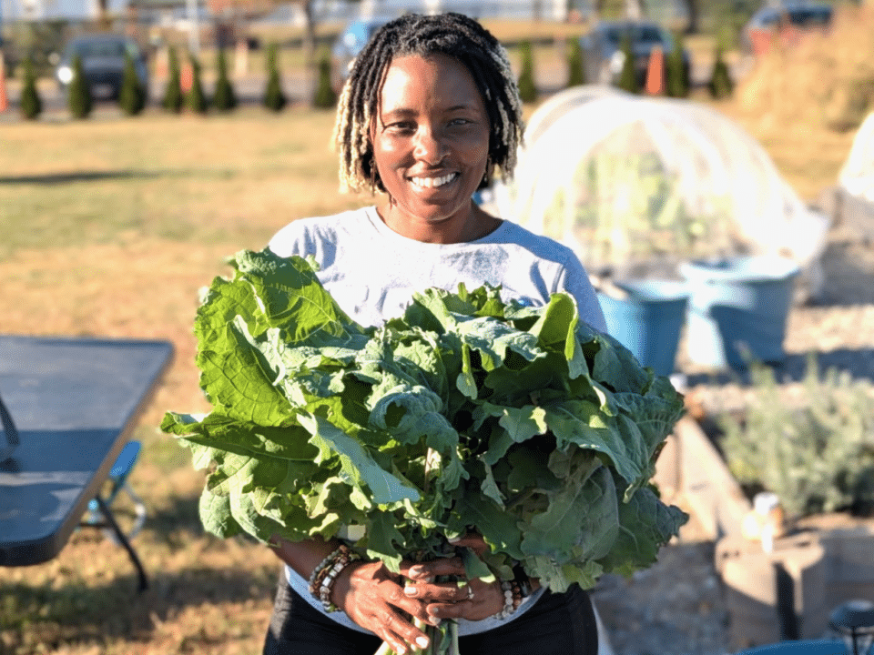 Stacey Woodson holds greens in a garden.